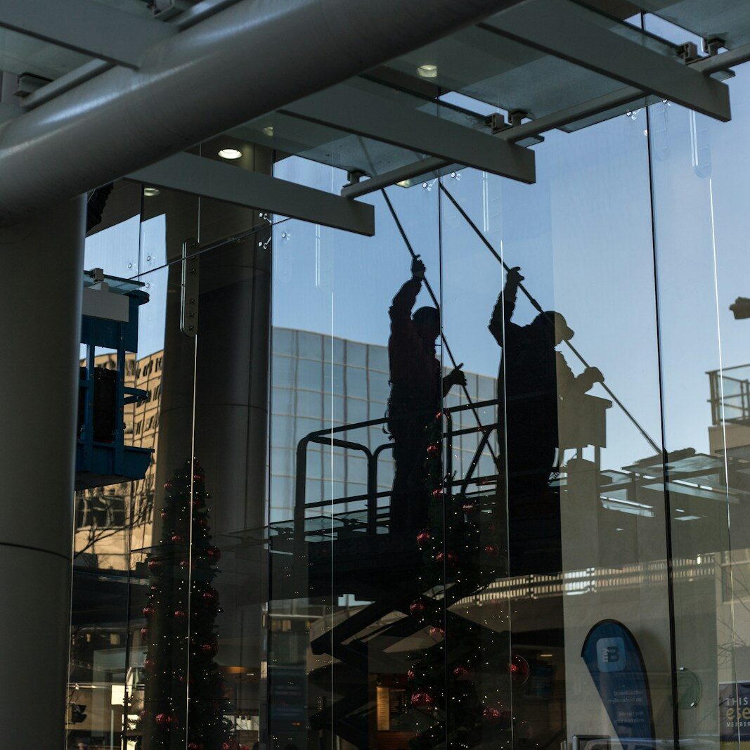 utility man standing in scissor platform cleaning glass window