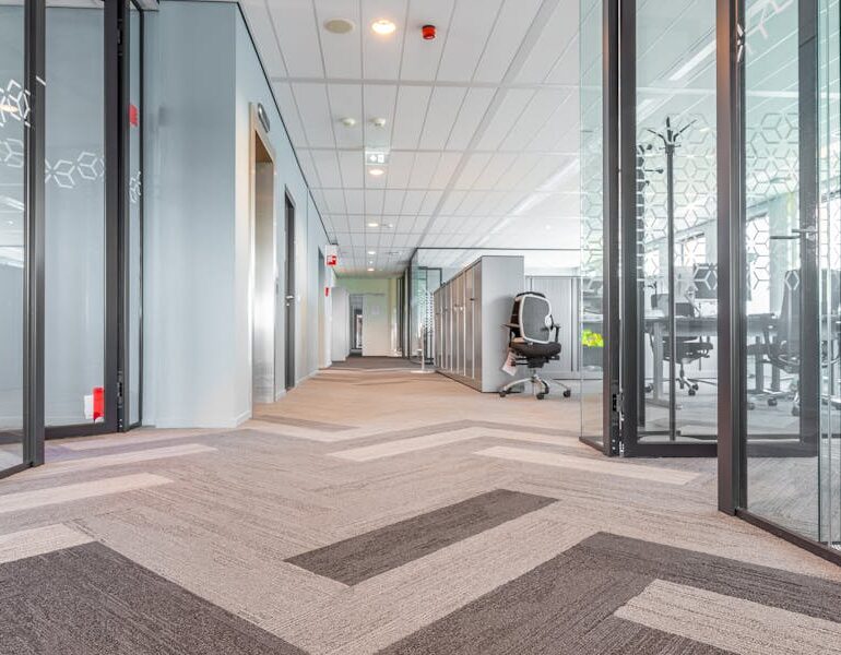 Spacious and bright modern office hallway with glass partitions and contemporary design.