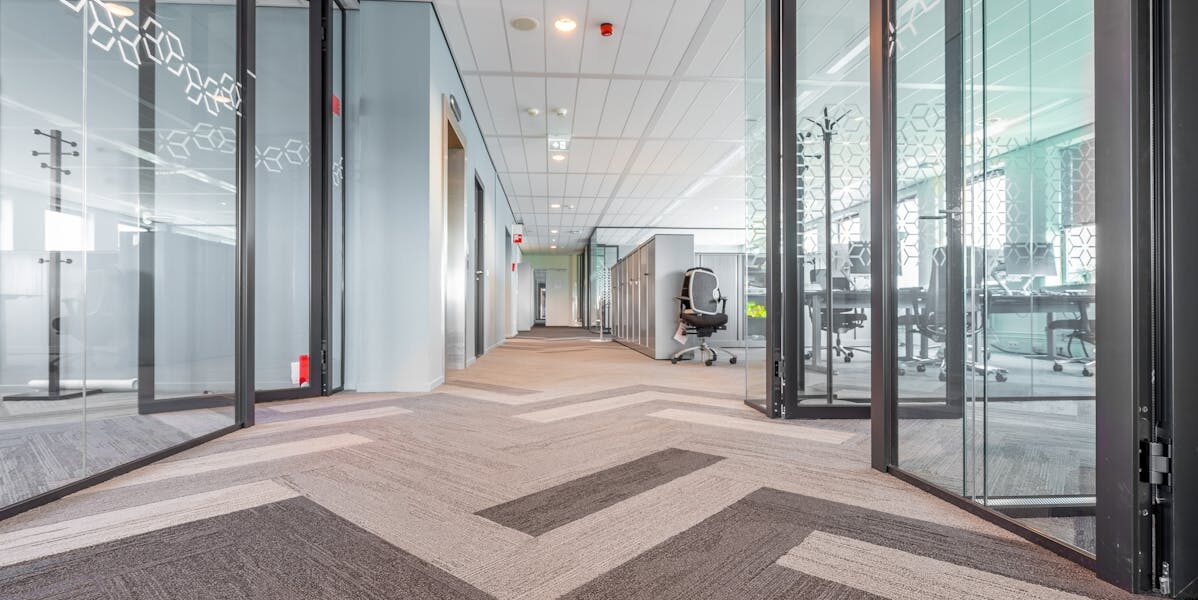 Spacious and bright modern office hallway with glass partitions and contemporary design.